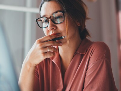 Young woman thinking while sitting in front laptop computer