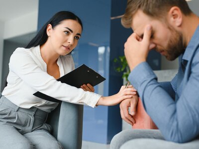 mental health professional holding a clipboard and working one-on-one with a male client
