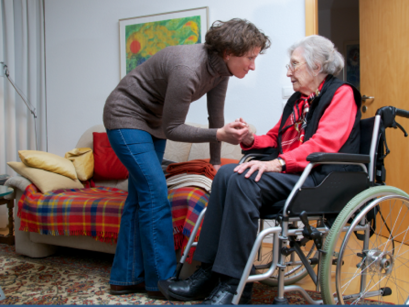social worker holding hand of an elderly woman in wheelchair