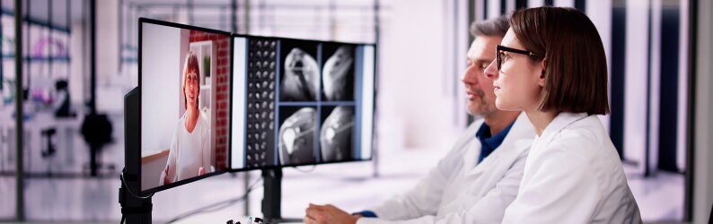 Two doctors are reviewing scans and consulting a patient via video call.