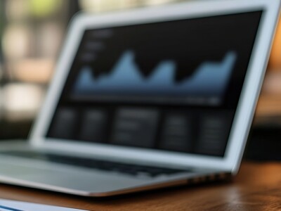 Close-up view of a desk setup with a smartphone, pens, and an open laptop displaying data analytics.
