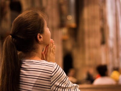 Young woman with a long pony-tail praying in a cathedral