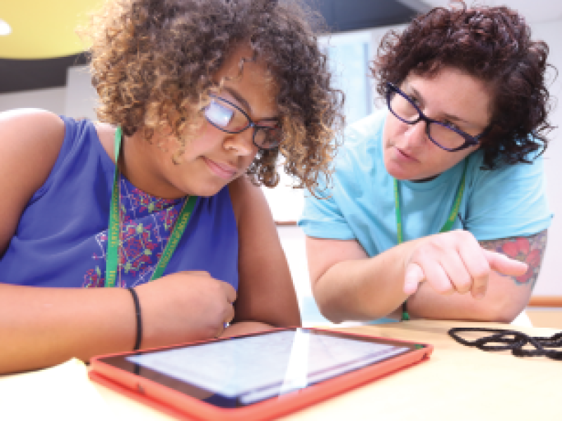 teacher with curly hair and glasses teaching female student