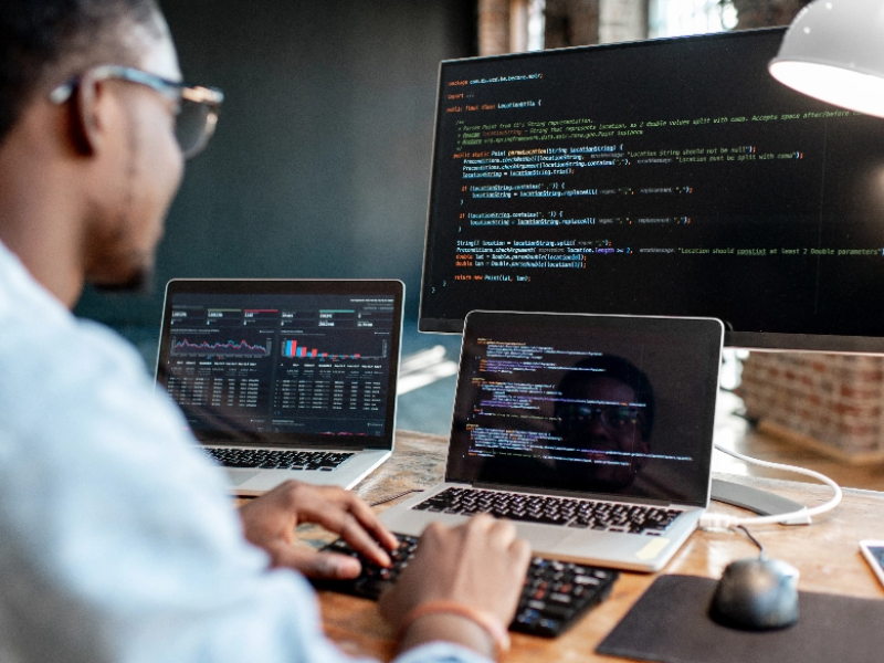 man working on multiple computers and screens