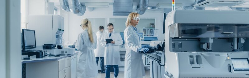 Team of Bioengineers Working On Computer, Analyzing Genetic Material Samples with Special Machines in the Modern Laboratory.