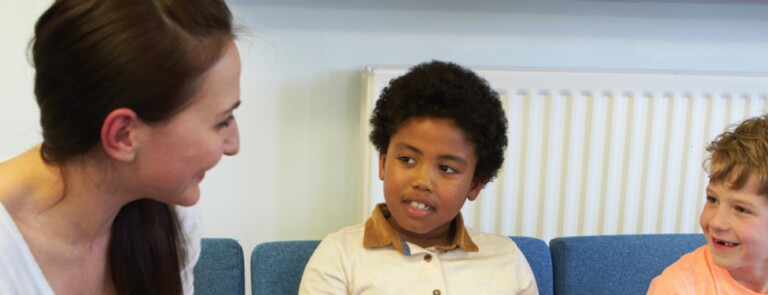 school counselor sitting down talking to two young boys