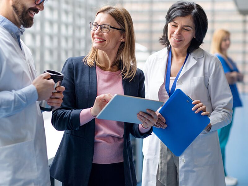 Female health care practitioner talking to two doctors