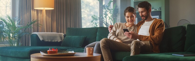 Couple using a smartphone to shop while sitting on a couch