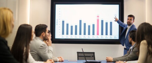 man-in-blue-suit-presenting-blue-and-red-bar-chart-to-audience