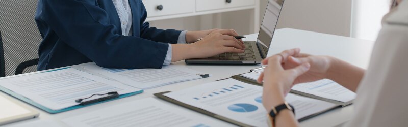 Two professionals reviewing financial charts and documents on wealth management during a business meeting.