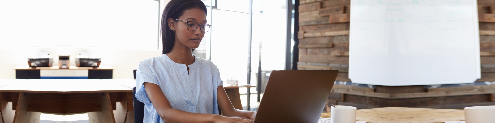 Woman works at kitchen table on her laptop
