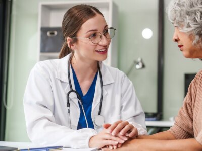 Female counselor sits at her desk providing mental health therapy and comfort to her female patient