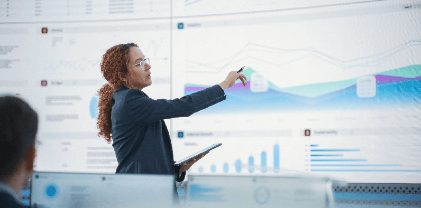 Woman in front of large projection screen describing graphs
