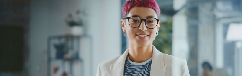 Person with dyed hair and glasses in casual business attire