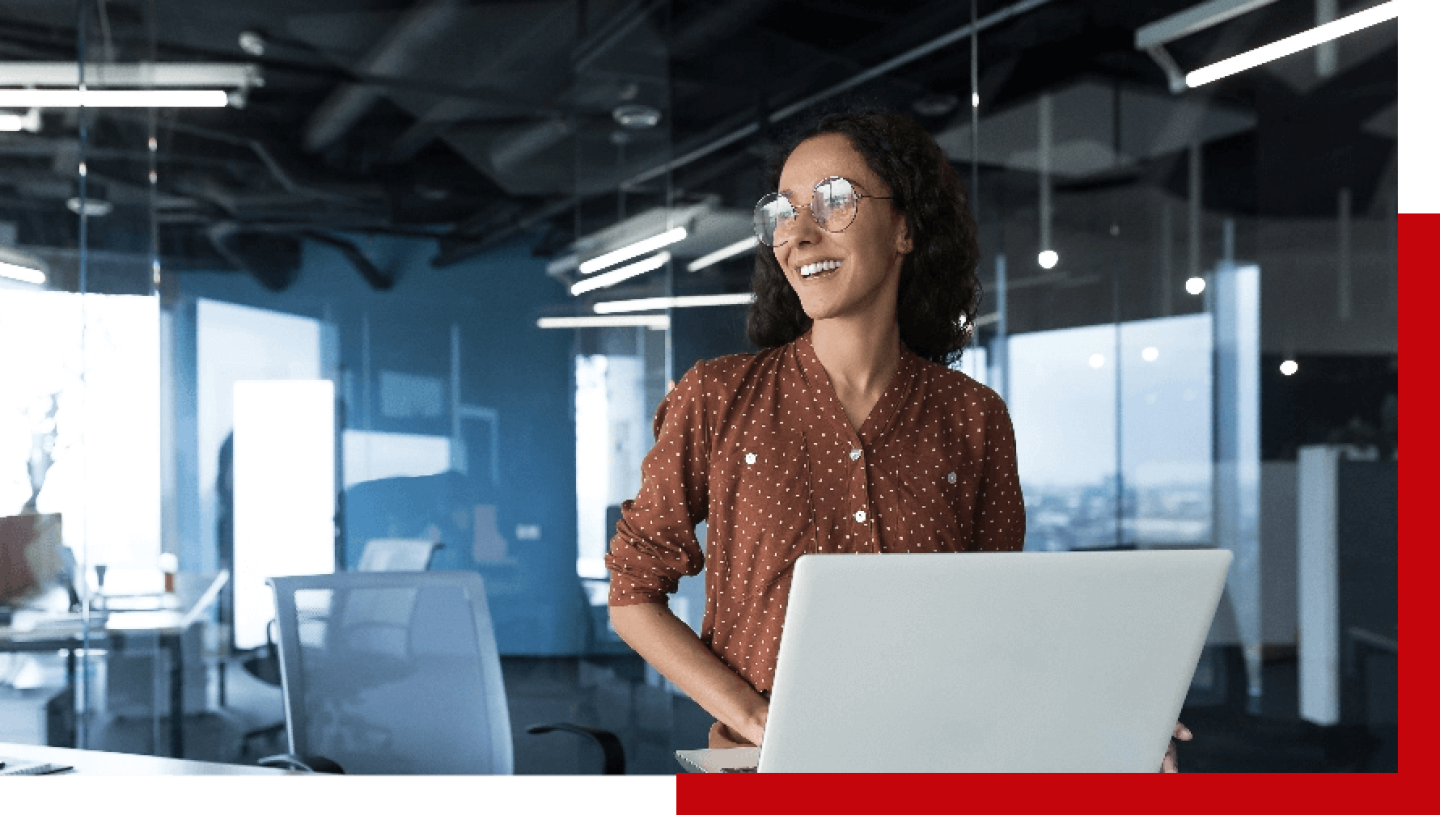 Woman in glasses smiling and using a laptop