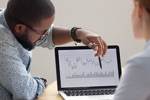 Two people examine graph data on a laptop screen