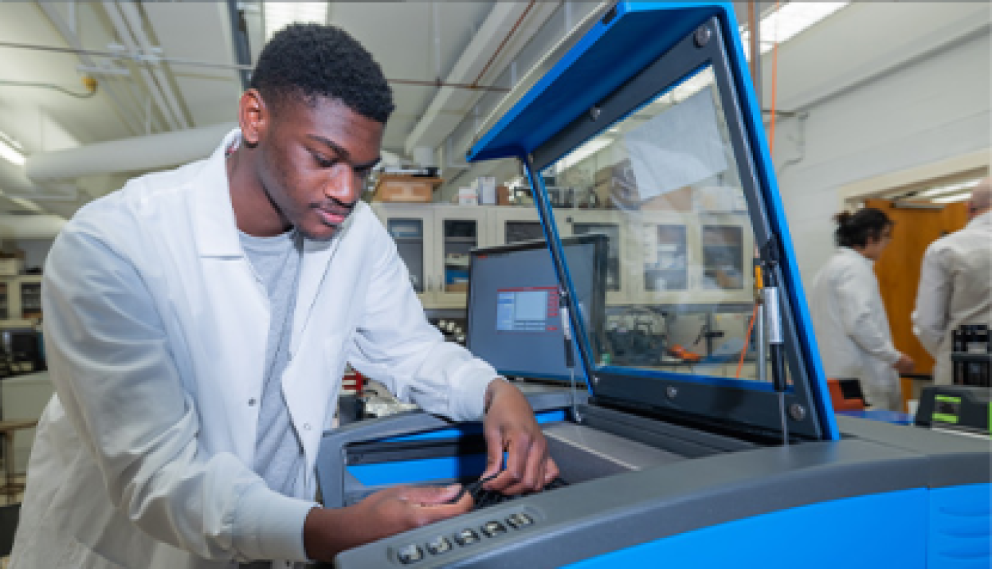 A male CWRU student setting up a machine in the fabrication workshop.