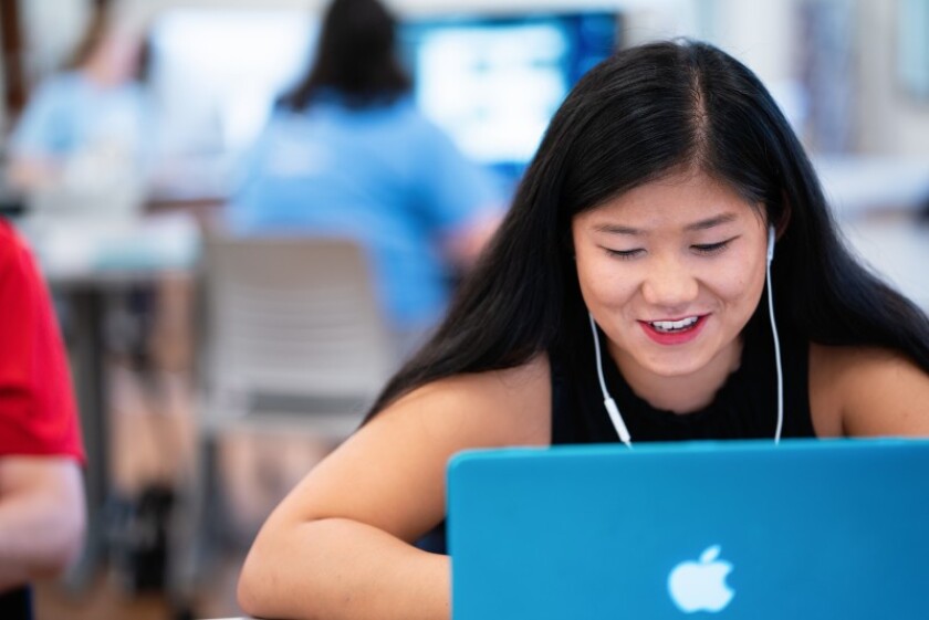Happy-student-working-on-laptop