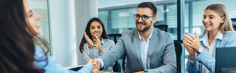 Business professionals in a sports management setting celebrate a successful interview with a handshake and applause.