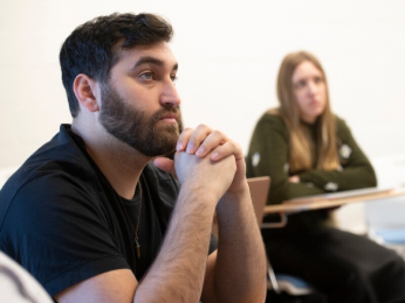 A male and female Yeshiva University student are listening to the professor during class.