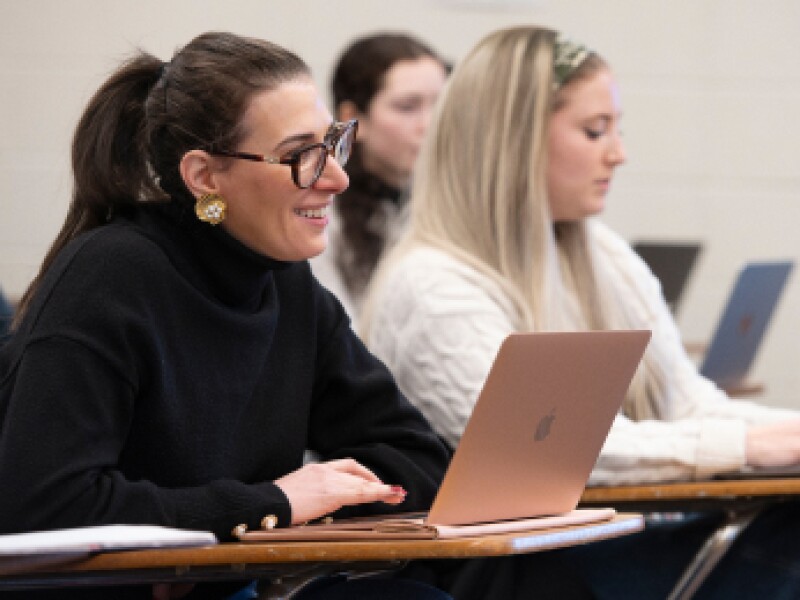 A close-up of female students listening to a professor.
