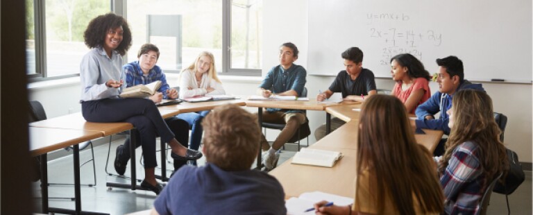 female teacher sitting with students in classroom