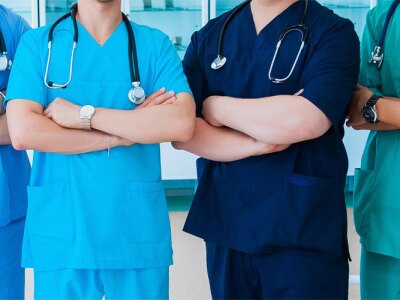 A group of faceless nurses stand together with arms crossed.