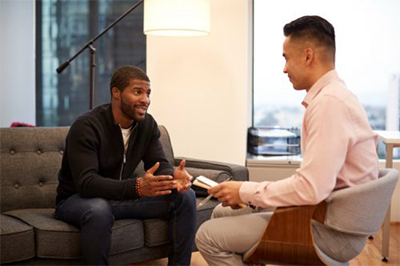 Two men sitting down talking to each other