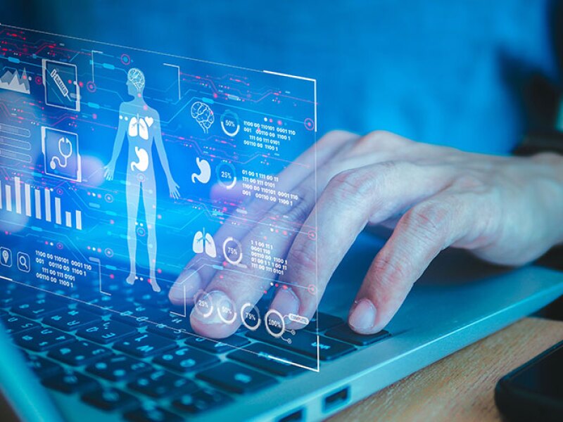 A futuristic screen is projected above a keyboard, illustrating a human body with various metrics displayed alongside it.