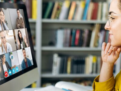 A female student learning online at home, focused watching a computer monitor.