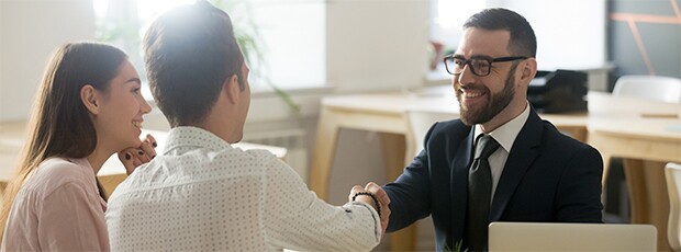 Man in suit smiling and shaking hands with couple
