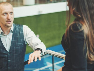 A lively conversation between two business partners with selective focus on a man entrepreneur with a laptop talking to his female colleague.