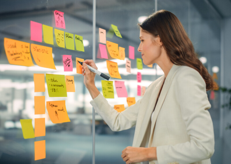 Woman standing in front of glass wall covered in post-it notes