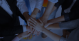 Group of hands stacked in the middle of circle of people