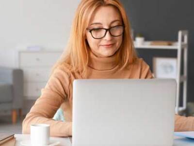 Graduate student taking notes while seated at. laptop