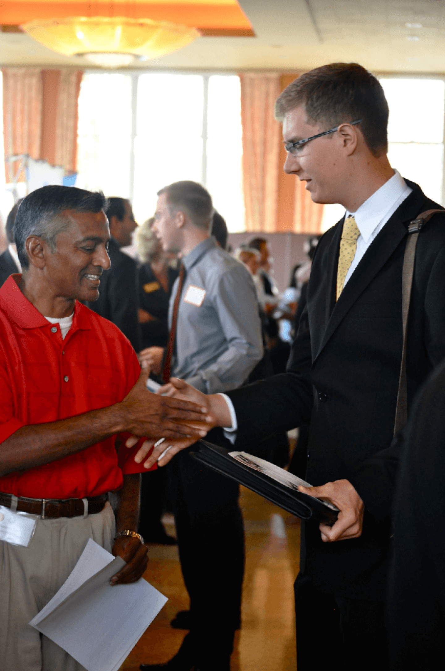 Man in suit shaking hands with man in polo shirt at networking event