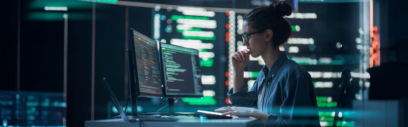 A woman looking at code on a computer monitor.