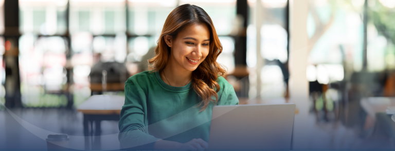 Woman in bright room looking at laptop and smiling