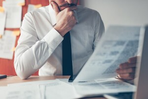 Businessman reading business report document at office desk.