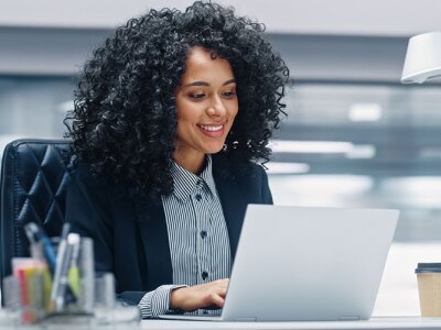 Black Businesswoman Sitting at Her Desk Working on a Laptop Computer.