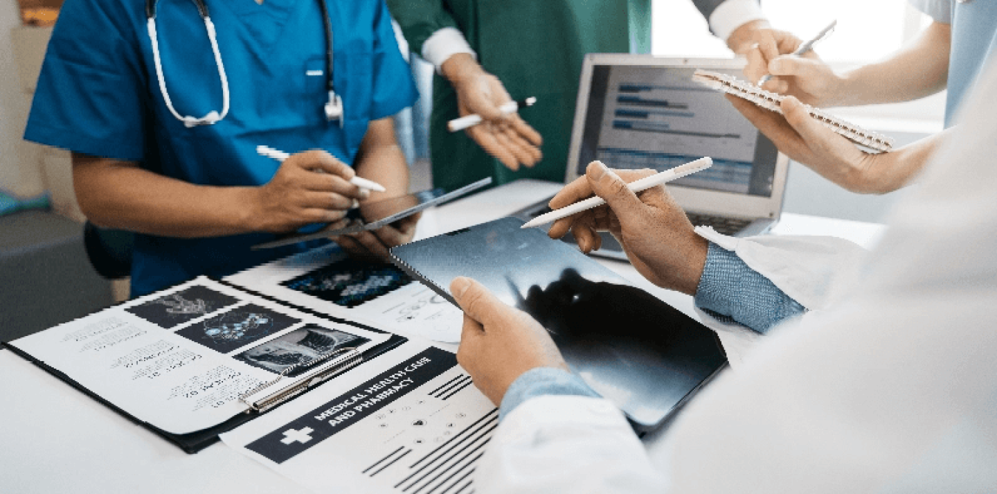 Nurses and doctors around a counter writing on tablets and looking at clipboards