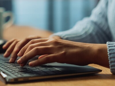 Close up on hands of a female working on a laptop in her living room