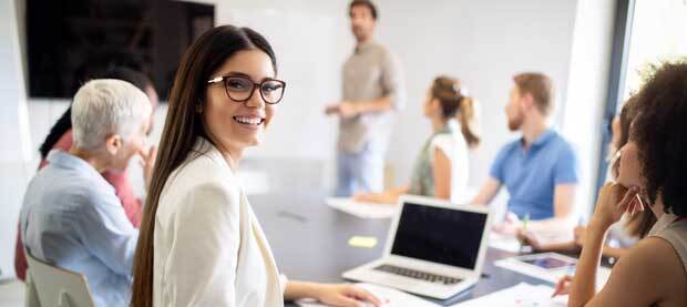 Smiling student in class, seated at a laptop
