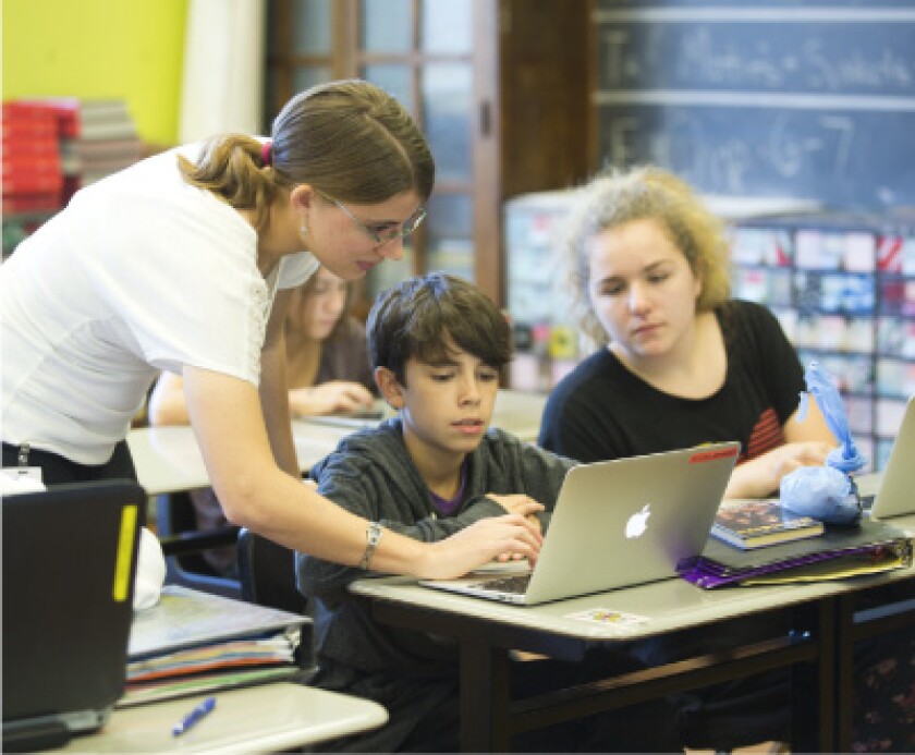 Female educator works with student on laptop