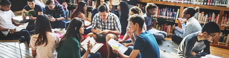 Group of students in a library reading and talking