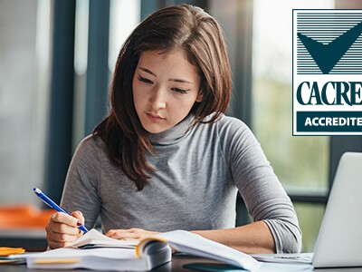 Young woman writing and studying with open books