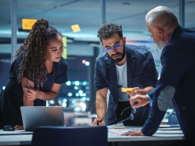 A diverse team of executives discuss financial investments during a night meeting.