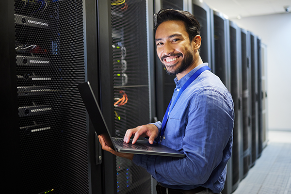 Man using laptop in front of server rack