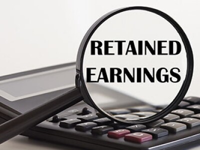 Focused on Retained Earnings concept. Magnifier glass with text on calculator.
