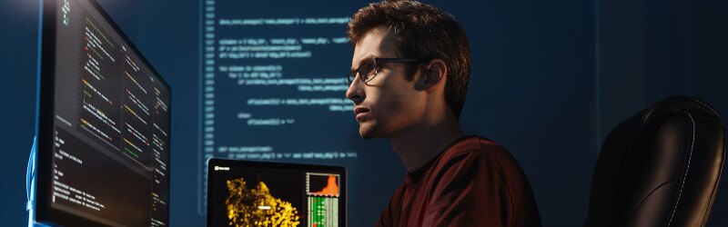 An engineer focused on code on multiple monitors.